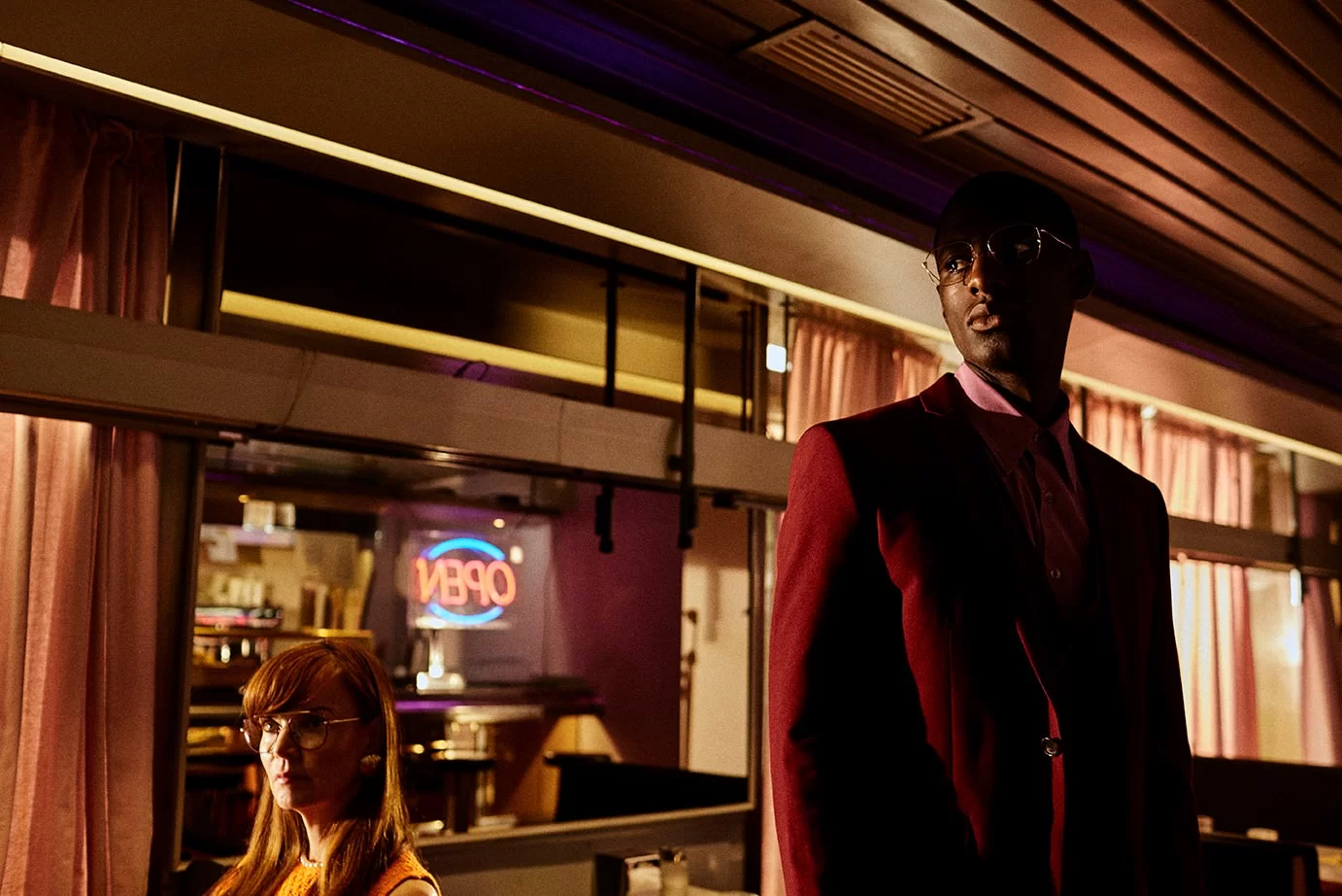 Brillenmarke Gigi Barcelona - Mann in rotem Anzug und Frau in Restaurant mit Brillen