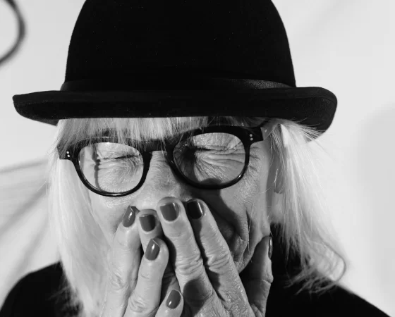 Lesebrille - Ältere Frau mit weißem Haar und Hut lacht - Portrait