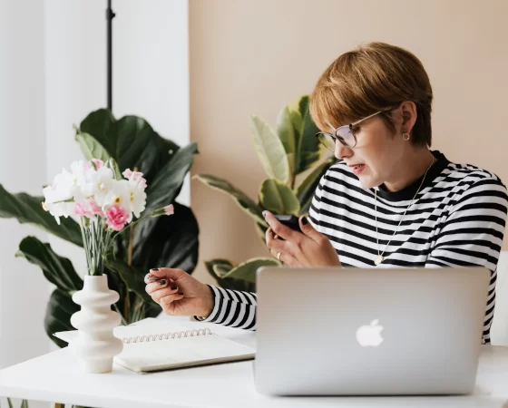 Arbeitsplatzbrille - Frau trägt Arbeitsplatzbrille und guckt auf Smartphone und Dokument